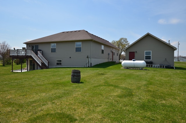 rear view of property featuring a lawn, a deck, and stairs