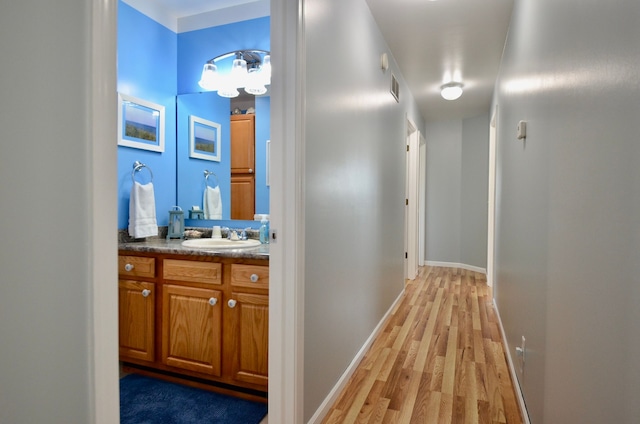 corridor featuring visible vents, light wood-style flooring, and a sink