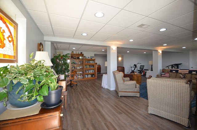 living area with wood finished floors, a paneled ceiling, and recessed lighting