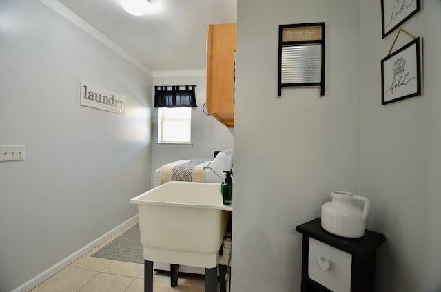 laundry area featuring crown molding, light tile patterned flooring, and baseboards