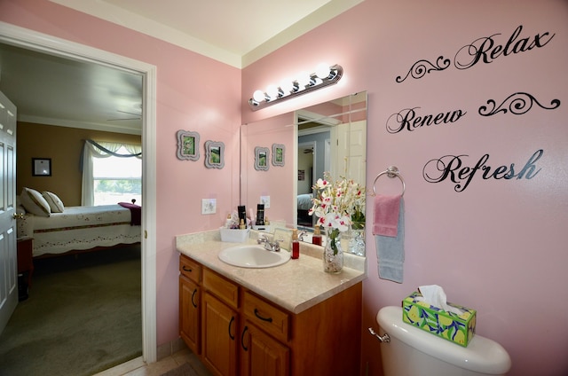 ensuite bathroom with toilet, vanity, crown molding, and ensuite bath