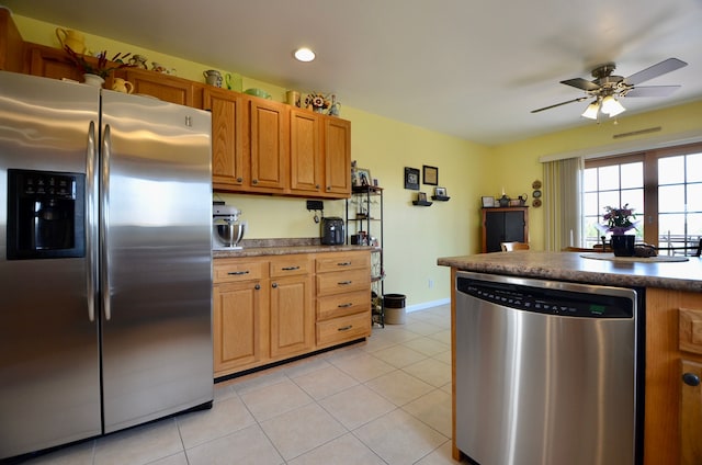 kitchen featuring brown cabinets, light tile patterned floors, a ceiling fan, baseboards, and appliances with stainless steel finishes
