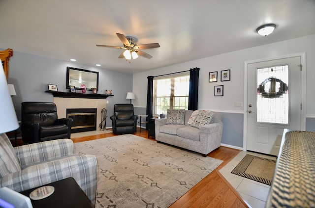 living room featuring a ceiling fan, wood finished floors, and a fireplace