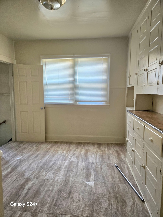 unfurnished dining area with baseboards, a healthy amount of sunlight, and wood finished floors