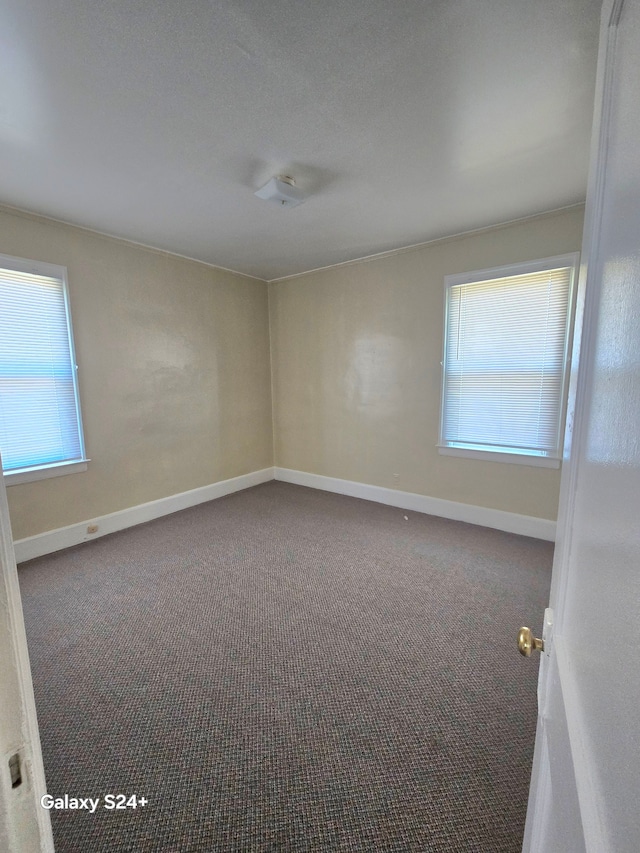 carpeted empty room featuring baseboards