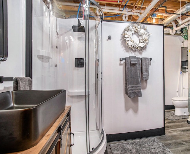 bathroom with toilet, a stall shower, wood finished floors, and vanity
