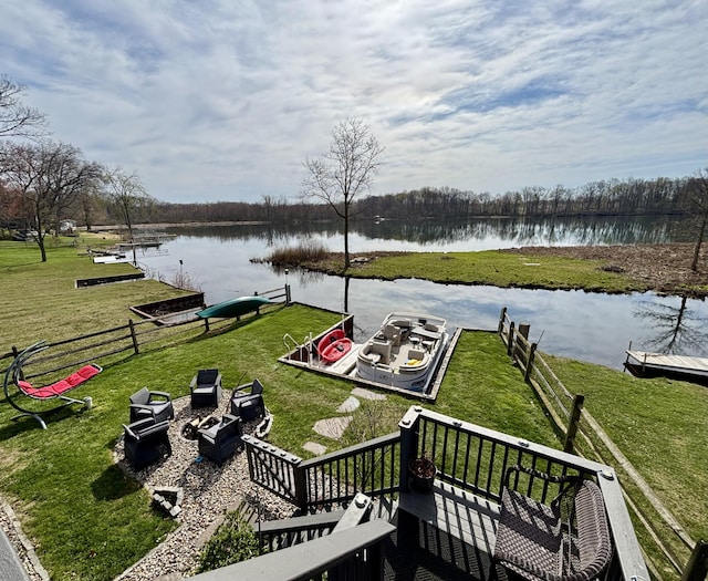 dock area with fence, a water view, and a lawn