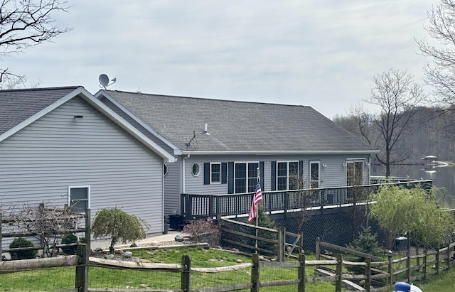 back of property with a wooden deck, a shingled roof, and fence
