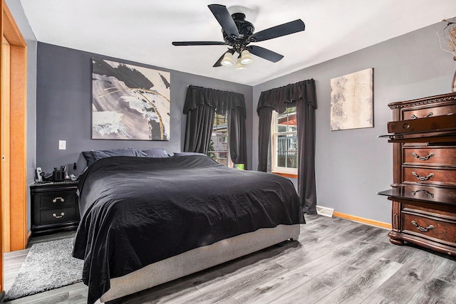 bedroom featuring wood finished floors, a ceiling fan, and baseboards