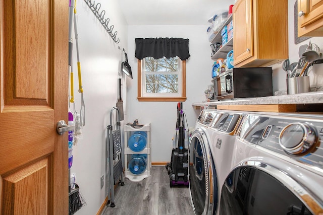 laundry area with baseboards, wood finished floors, cabinet space, and washing machine and clothes dryer