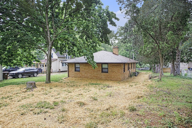 904 W Walnut St, Hastings, MI 49058 - view of side of home with a chimney, a yard, brick siding, and a shingled roof
