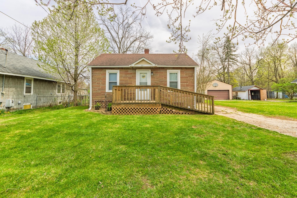 bungalow-style house with a chimney, brick siding, a detached garage, and a front yard