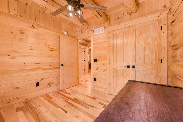 spare room featuring beam ceiling, ceiling fan, visible vents, wood walls, and wood finished floors