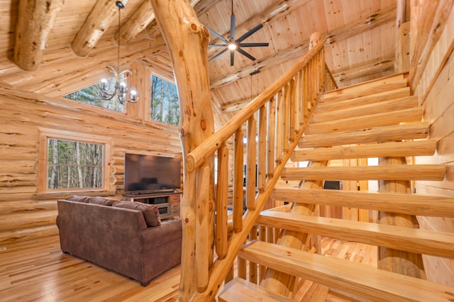 staircase with a notable chandelier, log walls, wood-type flooring, beam ceiling, and high vaulted ceiling