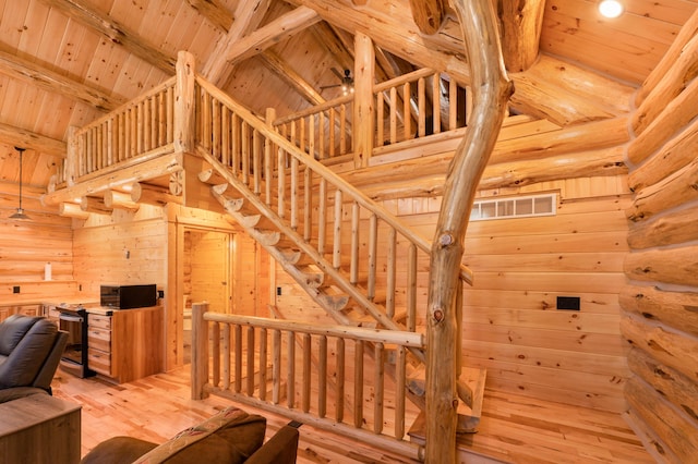 unfurnished living room featuring high vaulted ceiling, beamed ceiling, light wood-style floors, and wood ceiling