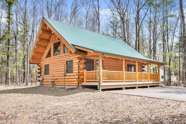 log cabin with log siding, metal roof, and a porch