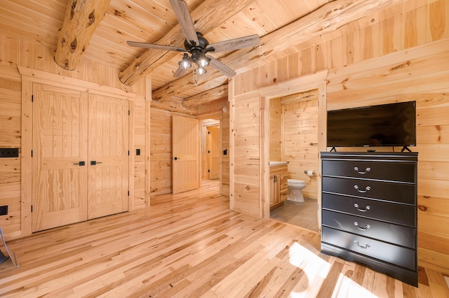 unfurnished bedroom with beamed ceiling, wooden ceiling, wooden walls, wood finished floors, and ensuite bath