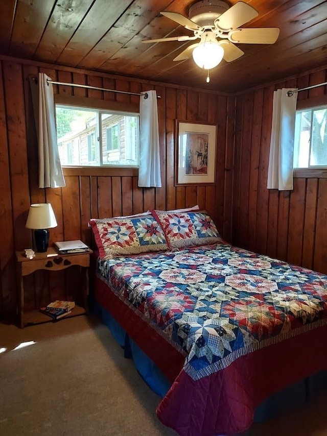 bedroom featuring wooden walls, carpet floors, a ceiling fan, and wooden ceiling