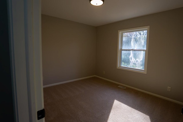 spare room with visible vents, carpet, and baseboards