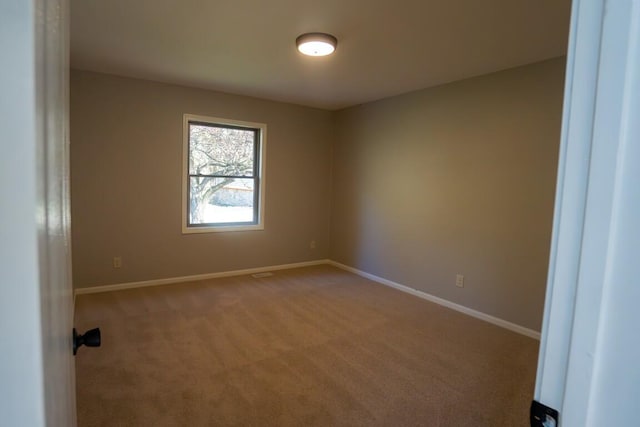 spare room with light carpet and baseboards