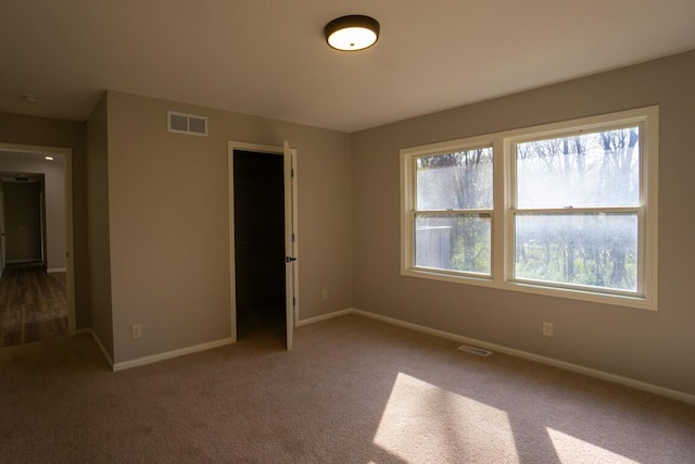 carpeted empty room with visible vents and baseboards