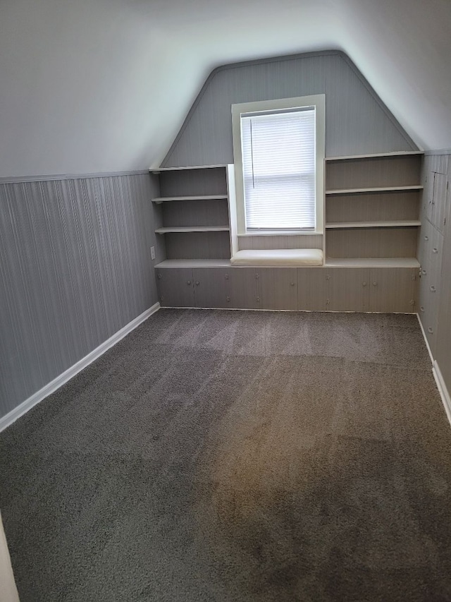 bonus room with dark carpet and vaulted ceiling