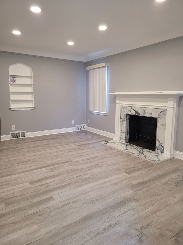 unfurnished living room with a premium fireplace, recessed lighting, visible vents, and baseboards