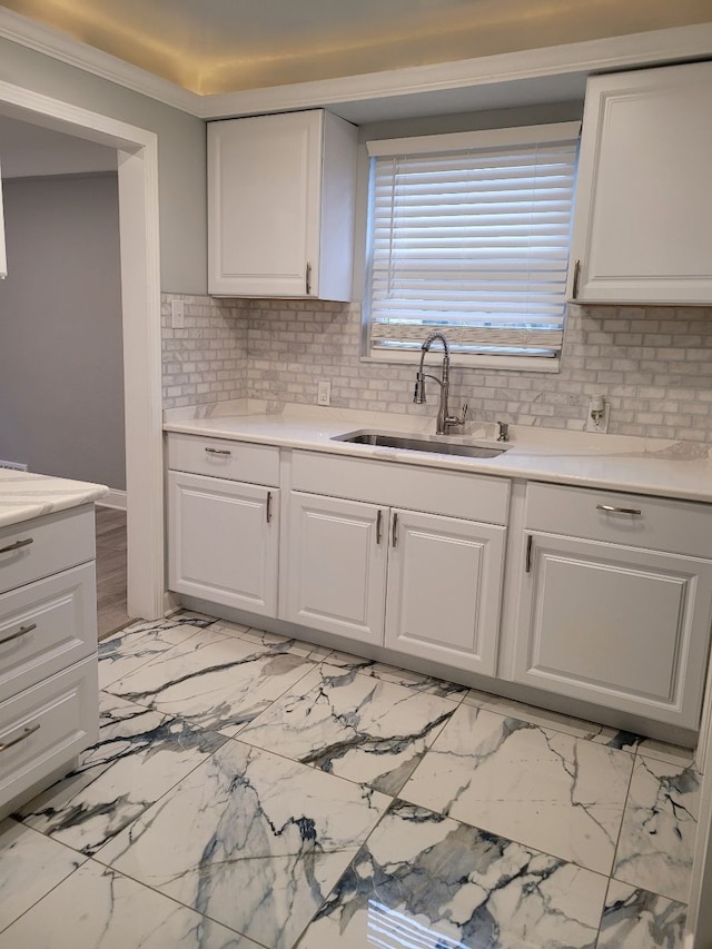 kitchen with tasteful backsplash, white cabinets, light countertops, and a sink