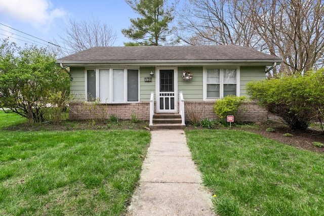 view of front of house with roof with shingles and a front yard