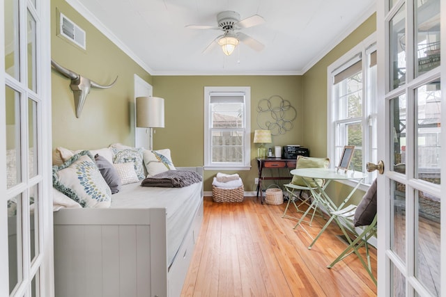 interior space featuring visible vents, crown molding, light wood-style flooring, and a ceiling fan