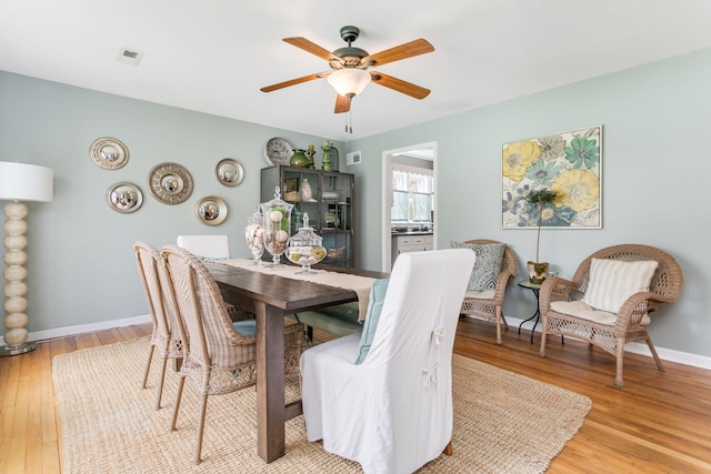dining space with light wood-style floors, a ceiling fan, visible vents, and baseboards