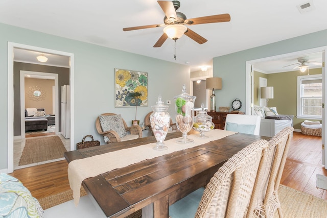 dining space with baseboards, visible vents, a ceiling fan, and light wood finished floors
