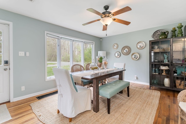 dining area with wood finished floors, visible vents, a ceiling fan, and baseboards