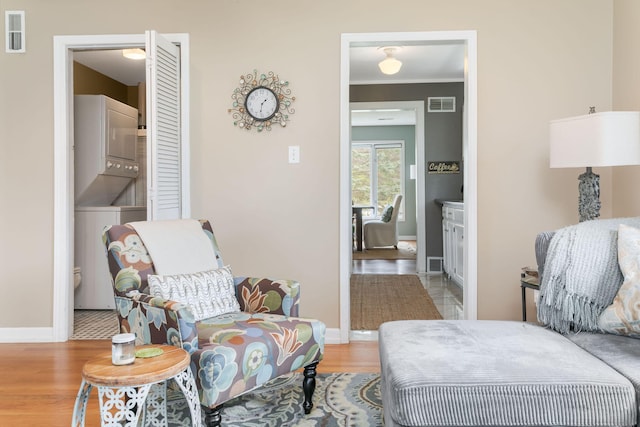 sitting room featuring visible vents, stacked washer and clothes dryer, and baseboards