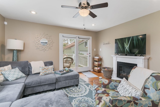 living room featuring recessed lighting, a ceiling fan, wood finished floors, and a glass covered fireplace
