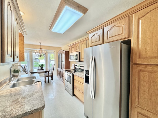 kitchen featuring light brown cabinets, a chandelier, stainless steel appliances, a sink, and pendant lighting