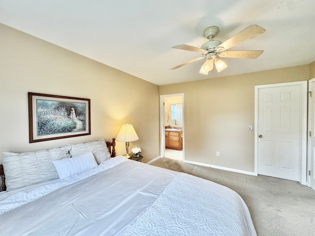 bedroom with ensuite bathroom, ceiling fan, light carpet, and baseboards