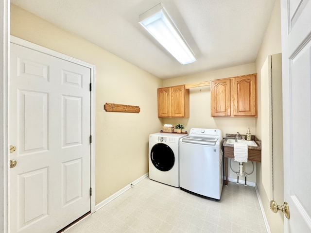 clothes washing area with baseboards, cabinet space, separate washer and dryer, and a sink