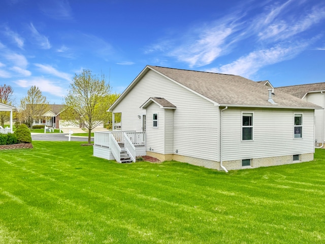back of property with a lawn and roof with shingles