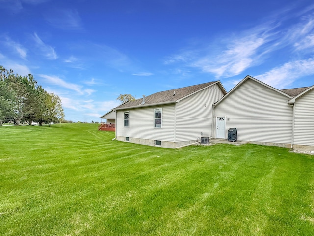 rear view of house featuring central air condition unit, a yard, and roof with shingles