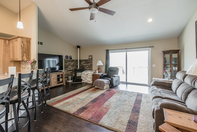 10207 Dodge Rd, Otisville, MI 48463 - living area with dark wood-style flooring, a wood stove, visible vents, a ceiling fan, and vaulted ceiling