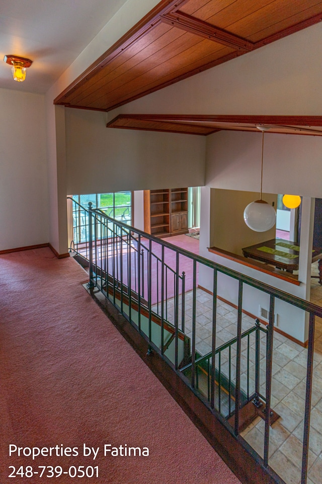 hall with carpet floors, lofted ceiling, baseboards, wood ceiling, and an upstairs landing