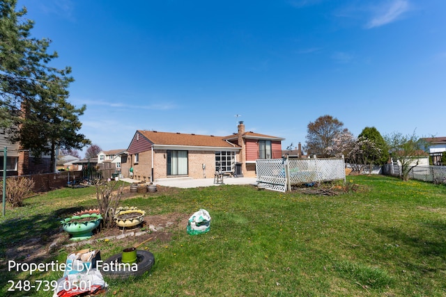 back of house featuring a lawn, a patio, a chimney, and a fenced backyard