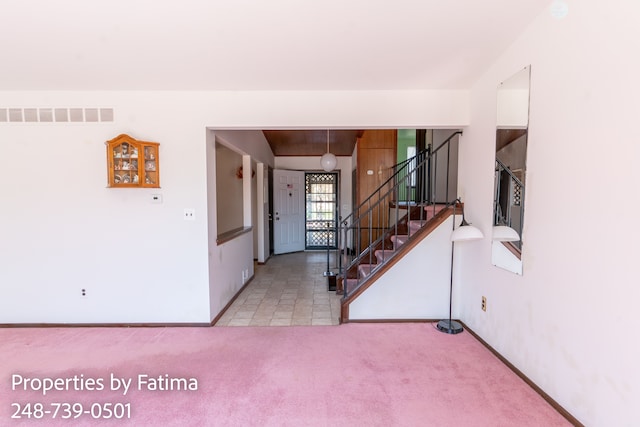 carpeted entrance foyer featuring visible vents, stairs, and baseboards