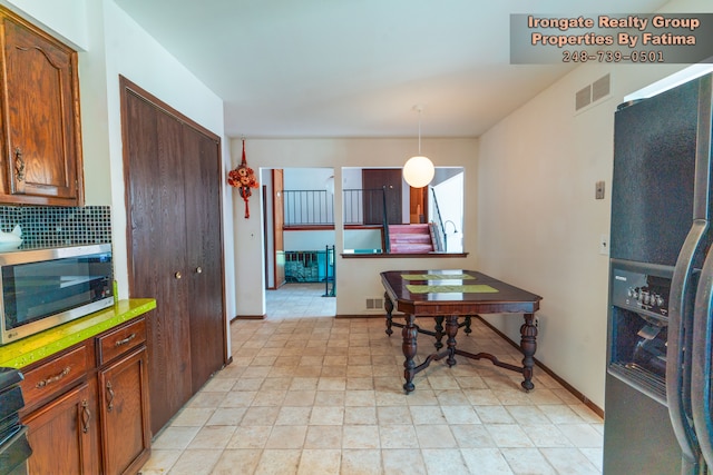 17906 Cider Mill St, Macomb, MI 48044 - kitchen with fridge with ice dispenser, stainless steel microwave, tasteful backsplash, decorative light fixtures, and baseboards