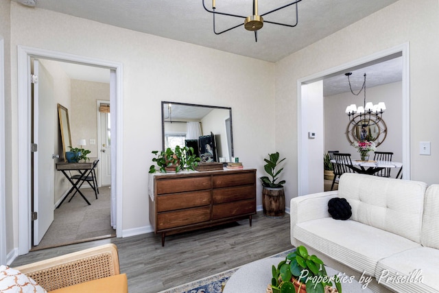 living area featuring a chandelier, wood finished floors, and baseboards