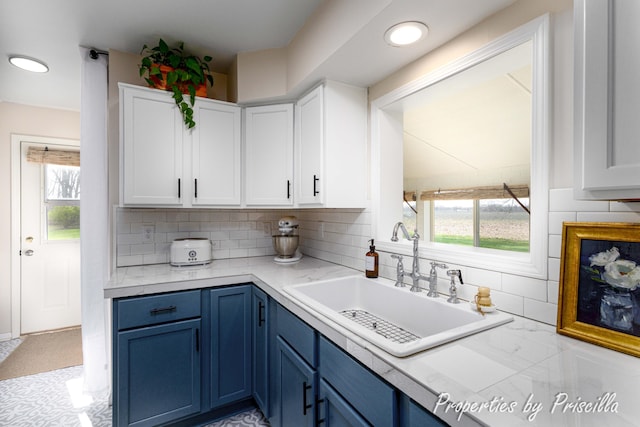 kitchen with light countertops, a sink, white cabinetry, and blue cabinetry
