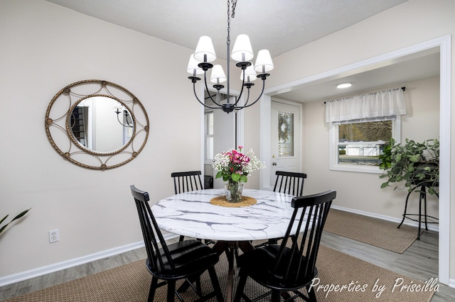 dining room with wood finished floors, a chandelier, and baseboards