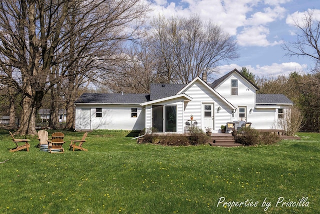 rear view of house featuring a lawn, a deck, and a shingled roof