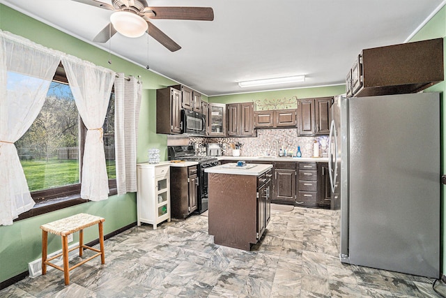 kitchen with ceiling fan, light countertops, a center island, black appliances, and dark brown cabinetry